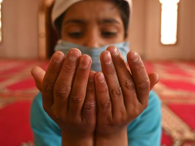 Seorang anak yatim Muslim mengenakan masker berdoa sambil menjaga jarak sosial di dalam pusat panti asuhan selama bulan suci Ramadan di Srinagar (11/5/2020). (AFP/Tauseff Mustafa)