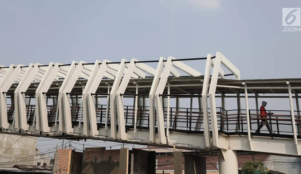Pekerja menyelesaikan pembangun jembatan Skybridge di Ramangun, Jakarta, Kamis (4/7/2019). Pembangunan Skybridge sudah 98 persen rampung, yang nantinya akan menghubungkan Stasiun Kereta LRT Velodrome dengan halte busway Pemuda Rawamangun akan rampung akhir bulan ini. (Liputan6.com/Faizal Fanani)