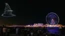 Kembang api menerangi langit selama upacara pembukaan Dubai Eye, yang dikenal sebagai Ain Dubai, di kota Emirat, dekat Dubai Marina, Kamis (21/10/2021). Bianglala terbesar dan tertinggi di dunia tersebut resmi dibuka untuk umum. (Giuseppe CACACE / AFP)