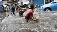 Sejumlah anak bermain banjir di kawasan Kemang Utara, Jakarta Selatan, Rabu (20/7). Banjir yang menggenangi sejumlah kawasan di Jakarta dijadikan kolam renang gratis bagi sejumlah anak. (Liputan6.com/Yoppy Renato)