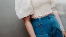 Berpose di antara rak buku perpustakaan, Tiara tampil anggun mengenakan blouse lengan puff berhiaskan mutiara yang memancarkan kesan elegan dan feminin.