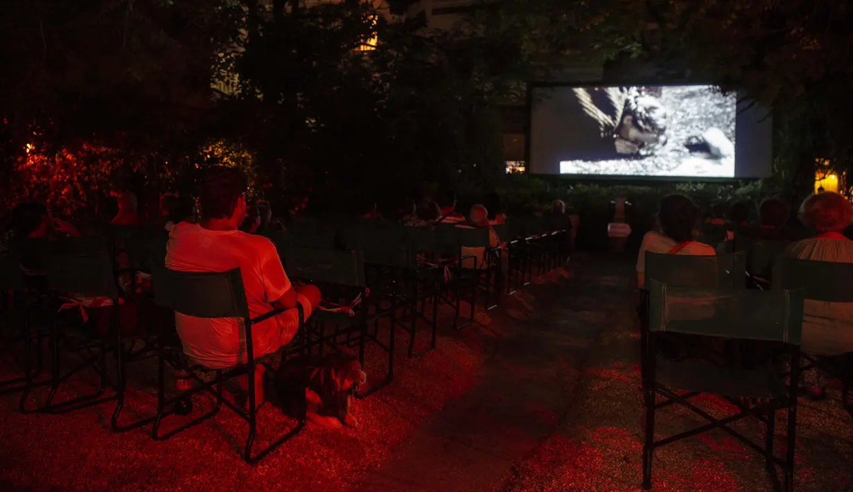 Penonton menonton film di bioskop terbuka Oasis, Athena, Yunani, 1 Agustus 2020. Pandemi COVID-19 memaksa bioskop terbuka dipersingkat sehingga menyebabkan penurunan jumlah penonton. (ANGELOS TZORTZINIS/AFP)