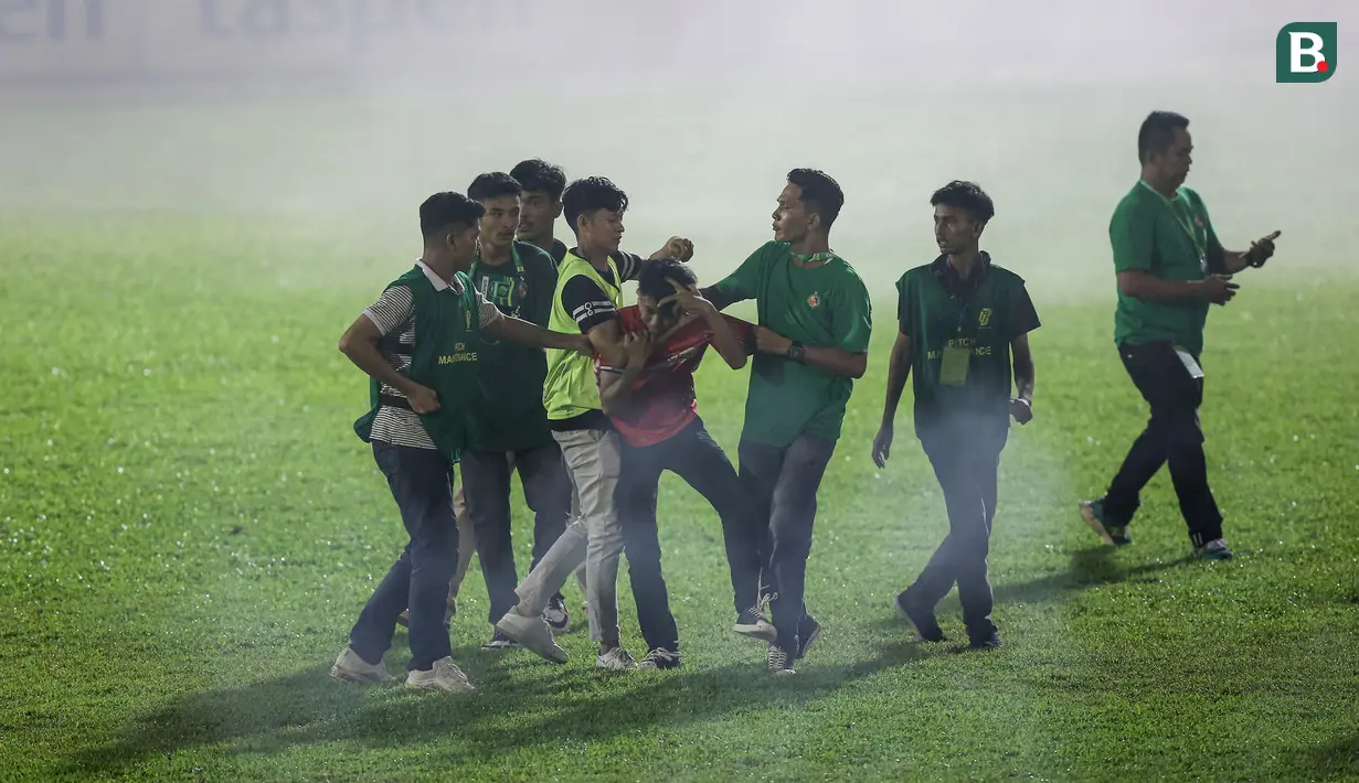 <p>Petugas keamanan lapangan berusaha menghentikan seorang suporter yang memasuki lapangan saat berlangsungnya laga leg kedua final Pegadaian Liga 2 2023/2024 antara Semen Padang mengadapi PSBS Biak di Stadion GOR Haji Agus Salim, Padang, Sabtu (9/3/2024). (Bola.com/Bagaskara Lazuardi)</p>