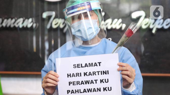 Tenaga medis menunjukkan bunga mawar dan ucapan selamat Hari Kartini di RSUD Kota Tangerang, Selasa (21/4/2020). Komunitas Taman Potret Tangerang menyambut Hari Kartini dengan mendatangi RSUD Kota Tangerang untuk memberikan bunga dan APD kepada tenaga medis perempuan. (Liputan6.com/Angga Yuniar)