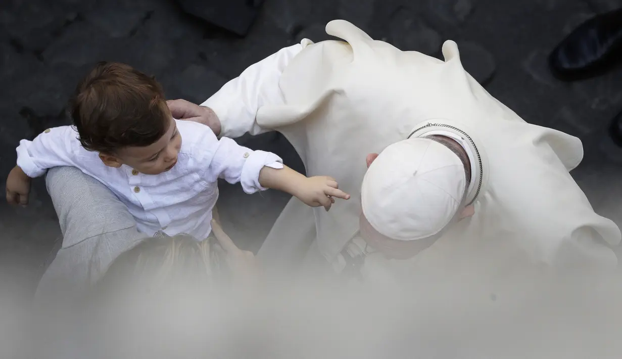 Seorang anak menjangkau Paus Fransiskus saat ia menyapa umat beriman di halaman St. Damaso pada kesempatan audiensi umum mingguan di Vatikan, Rabu (16/9/2020). (AP Photo/Gregorio Borgia)