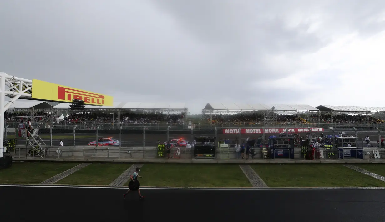 Seorang kru berlari ke paddock saat hujan lebat sebelum Race 2 WSBK Mandalika 2021 di Pertamina Mandalika International Street Circuit, Lombok, Nusa Tenggara Barat, Minggu (21/11/2021). Balapan dilanjutkan pukul 15.30 WIB atau 16.30 Wita dan hanya digelar 12 lap. (AP Photo/Achmad Ibrahim)