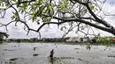 Amir (38) saat menjala ikan di genangan air yang merendam kompleks pemakaman TPU Semper, Jakarta, Selasa (2/2/2021). Banjir yang semakin tinggi merendam TPU Semper hingga mencapai sepinggang orang dewasa. (merdeka.com/Iqbal S. Nugroho)