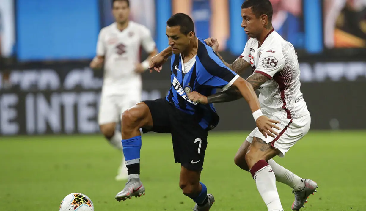 Striker Inter Milan, Alexis Sanchez, berebut bola dengan pemain Torino, Armando Izzo, pada laga Serie A di Stadion Giuseppe Meazza, Senin (13/7/2020). Inter Milan menang 3-1 atas Torino. (AP Photo/Luca Bruno)