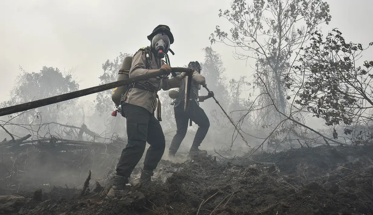 Polisi yang mengenakan perlengkapan pemadam kebakaran memadamkan kebakaran lahan gambut di Tambang, Kabupaten Kampar, Provinsi Riau, Selasa,  25 Agustus 2026. (AFP/ Wahyudi)