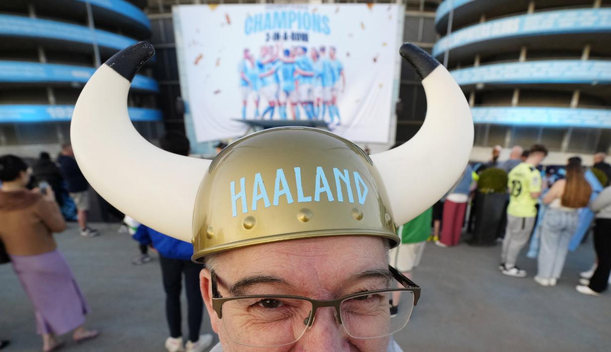 Seorang suporter memakai topi bertuliskan pemain Manchester City, Erling Haaland, saat merayakan gelar juara Liga Inggris di depan Stadion Etihad, Sabtu (20/5/2023). City memastikan gelar juara setelah Arsenal dikalahkan Nottingham Forest dengan skor 0-1 pada lanjutan Liga Inggris 2022/2023 hari Minggu (21/05/2023). (AP Photo/Jon Super)