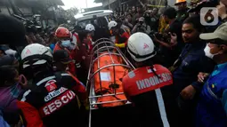 Petugas mengevakuasi jasad yang ditemukan pasca-kebakaran hebat Depo Pertamina Plumpang, Koja, Jakarta Utara, Sabtu (4/3/2023) pagi. Api baru berhasil dipadamkan sekitar pukul 00.00 WIB, Sabtu (4/3) dini hari tadi. (merdeka.com/Arie Basuki)