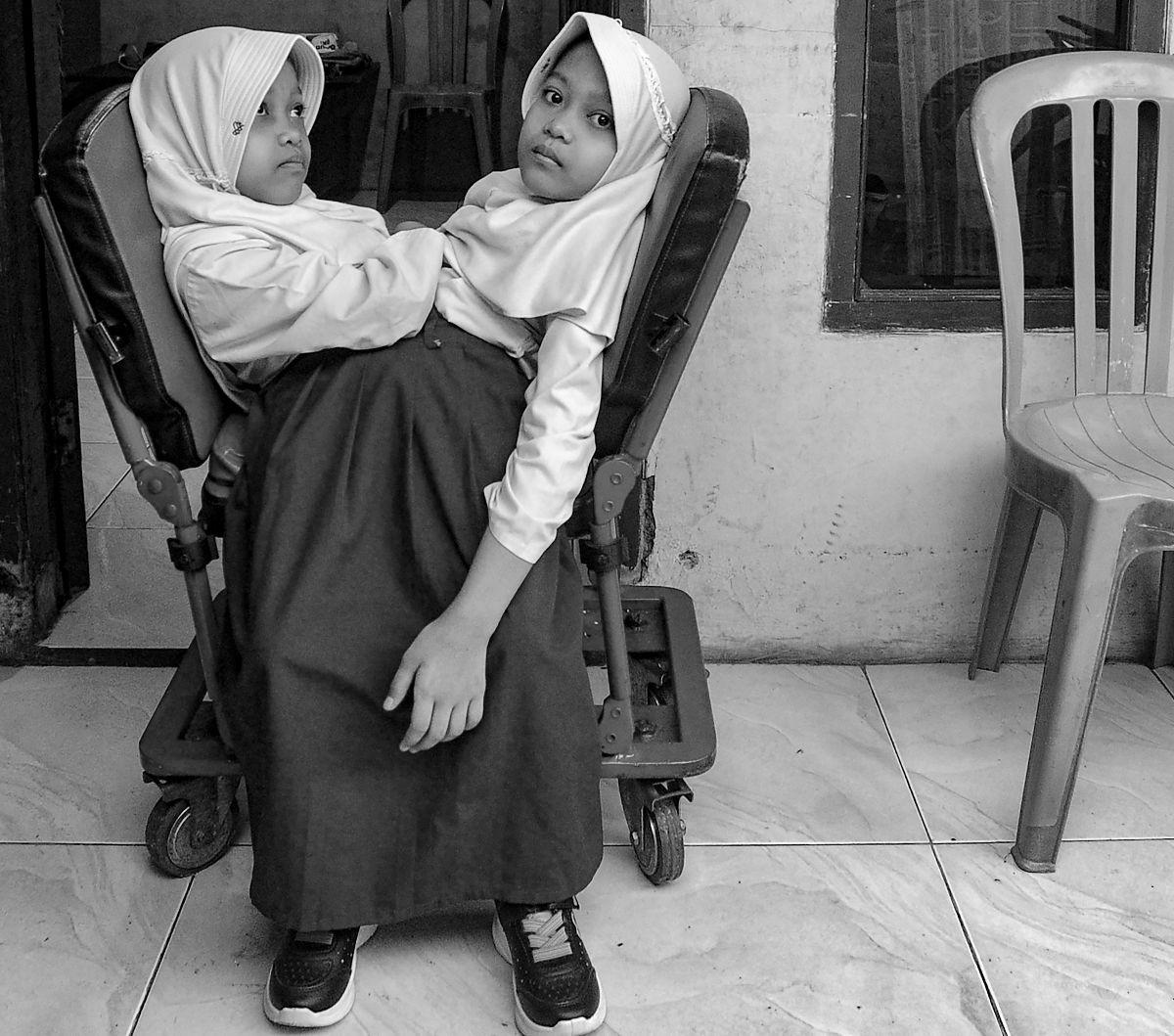Anak kembar siam Al Dewi Putri Ningsih (9) dan Al Putri Anugrah (9) menggunakan kursi roda khusus ketika bersiap berangkat ke sekolah di Garut, Jawa Barat, dalam foto yang diambil pada 22 Mei 2023. Al Dewi dan Al Putri terlahir dalam kondisi kembar siam d
