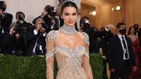 Kendall Jenner tampil bergaya ‘naked’ dalam balutan sheer gown bertabur kristal berkilau rancangan Givenchy. Penampilannya yang glamor tersebut diperlengkap dengan kalung choker besar. Model 25 tahun ini menjaga rambutnya tetap sederhana dengan sanggul rendah. (Instagram/_metgala2021).