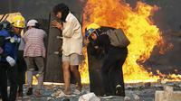 Para pengunjuk rasa berlindung di balik perisai buatan sendiri saat mereka menghadapi polisi selama tindakan keras terhadap demonstrasi menentang kudeta militer di Yangon, Myanmar, 16 Maret 2021. (STR/AFP)