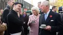Pangeran Charles bersama istrinya, Duchess of Cornwall Camilla menikmati teh sambil berbincang ketika mengunjungi Swiss Cottage Farmers Market di London utara, Rabu (6/11/2019). Kunjungan Charles dan Camila untuk mengucapkan selamat dan memperingati ulang tahun ke-20 pasar tersebut. (Eddie Mulhollan