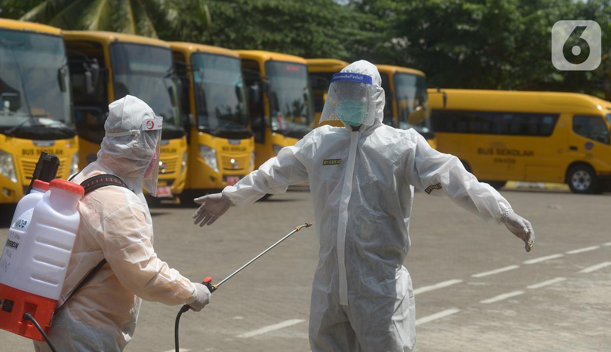 Petugas disemprot disinfektan sebelum menjemput pasien Covid-19 menggunakan bus sekolah di Puskesmas Jatinegara, Jakarta, Selasa (22/9/2020). Bus sekolah Pemprov DKI kini dialihfungsikan menjadi kendaraan untuk mengantar pasien Covid-19 berstatus OTG menuju Wisma Atlet. (merdeka.com/Imam Buhori)