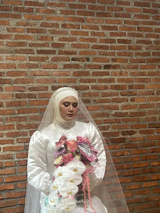 Sementara itu, sang kakak yang menjadi ratu sehari tampil anggun dengan gaun silk dan kerudung serba putih.