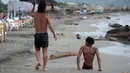 Imigran Venezuela, Alfonso Mendoza alias Alca (kanan) berjalan di pantai usai bermain surfing di Puerto, Kolombia, 27 September 2018. Musik dan teman membantunya untuk lebih optimis menjalani hidup. (Raul ARBOLEDA/AFP)