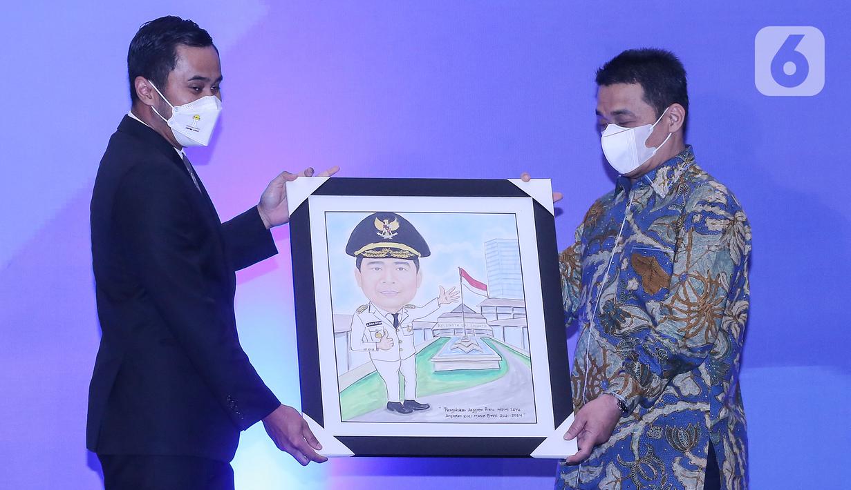 Ketua Umum BPD HIPMI Jaya Sona Maesana memberikan cenderamata lukisan karikatur kepada Wakil Gubernur DKI Jakarta Riza Patria pada Pengukuhan Anggota Baru HIPMI Jaya Angkatan 2021 di The Tribrata Darmawangsa, Jakarta, Kamis (02/12/2021). (Liputan6.com/Fery Pradolo)