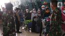 Petugas mengarahkan rombongan jemaah umrah yang tiba di Bandara Soekarno Hatta, Tangerang, Selasa (29/12/2020). Rombongan jemaah umrah yang baru tiba di Indonesia tersebut diarahkan untuk melakukan karantina di tempat yang telah disediakan oleh pemerintah. (Liputan6.com/Angga Yuniar)