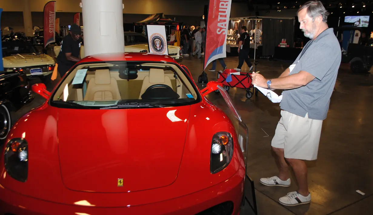 Pengunjung mengambil gambar mobil Ferrari F430 yang dipamerkan oleh Auctions America di Florida, 31 Maret 2017. Mobil berwarna merah menyala produksi 2007 itu pernah digunakan oleh Presiden AS, Donald Trump, selama empat tahun. (LEILA MACOR/AFP)