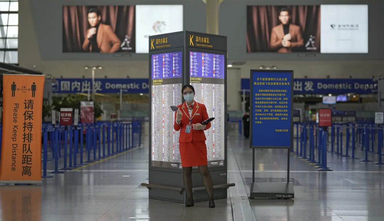 Staf pesawat yang mengenakan masker berdiri di dekat konter check-in yang sepi di Bandara Internasional Pudong, Shanghai, Minggu (25/7/2021). China telah menutup jalur kereta api dan pelabuhan, serta membatalkan jadwal penerbangan sebelum topan In-Fa diperkirakan mendarat. (AP Photo/Andy Wong)