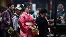Gambar pada 21 Oktober 2019 menunjukkan seorang perempuan mengenakan pakaian tradisional Jepang, kimono, saat mengunjungi kuil Senso-ji di Tokyo. Sensoji Temple merupakan salah satu kuil tertua di Jepang yang terletak di Asakusa. (Anne-Christine POUJOULAT / AFP)