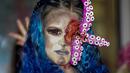 Seorang perempuan yang mengenakan kostum menakutkan berpartisipasi dalam Zombie Walk dan Parade Halloween tahunan di Essen, Jerman, Minggu (31/10/2021). Setiap 31 Oktober sebagian masyarakat dunia ikut memeriahkan perayaan Halloween. (AP Photo/Martin Meissner)