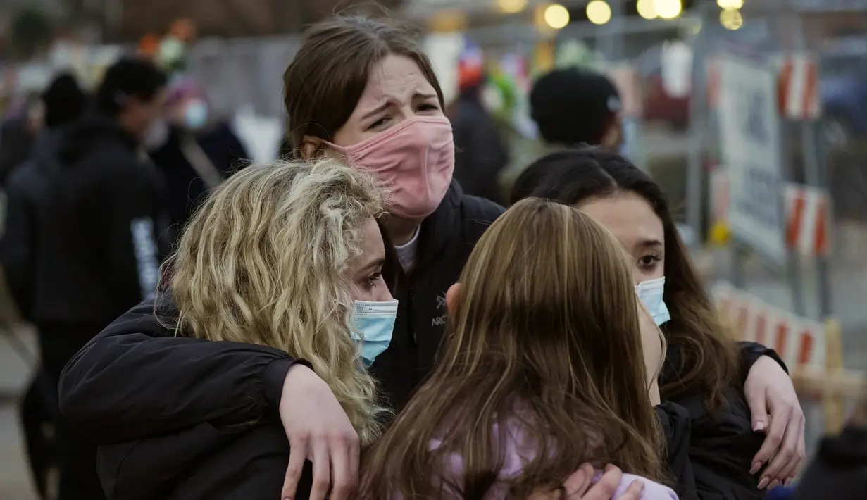 Warga saling menghibur di sepanjang pagar yang dipasang di sekitar tempat parkir tempat penembakan massal terjadi di toko King Soopers di Boulder, Colorado (23/3/2021). (AP Photo/David Zalubowski)