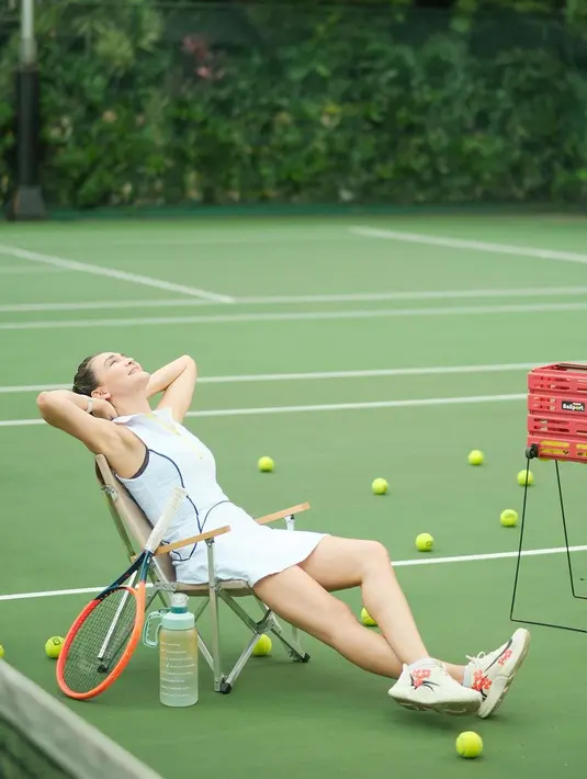 Luna Maya menjadi peserta dari episode Lagi-Lagi Tenis yang terbaru dan keluar sebagai pemenang. Dalam sebuah foto, dirinya terlihat duduk bersandar santai di kursi mengenakan outfit tenis berwarna putih berkerah tanpa lengan. Setelan atasan dan rok yang serasi dengan sedikit sentuhan warna hitam di bagian garis siluet tubuh. Luna Maya memadukannya dengan sepatu bernuansa putih dengan sentuhan warna oranye yang serasi. Foto: Instagram.