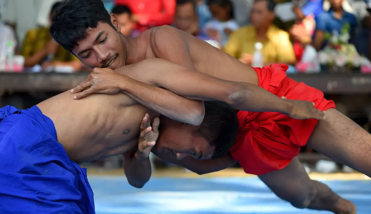 Dua pria bertarung gulat Khmer selama festival Pchum Ben atau festival kematian di desa Vihear Suor, provinsi Kandal (9/10). Warga Kamboja turun dari desa kecil di timur laut ibu kota untuk menyaksikan pertarungan ini. (AFP Photo/Tang Chhin Sothy)