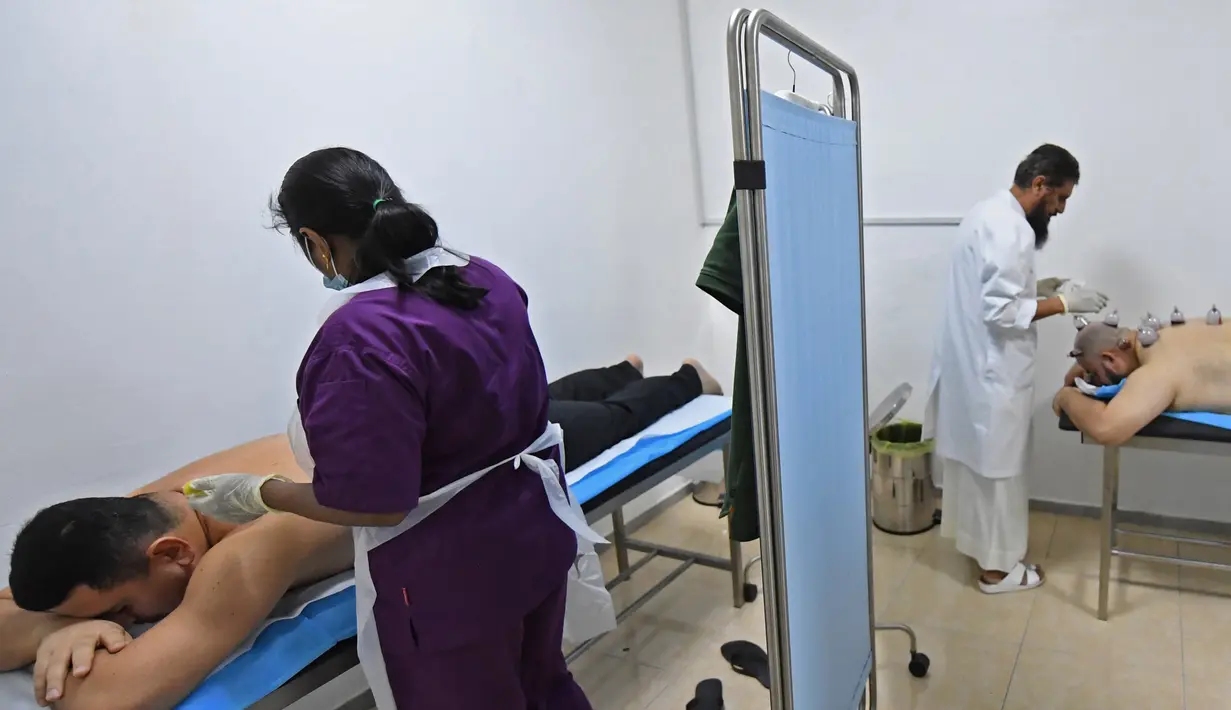 Spesialis melakukan pengobatan hijama atau terapi bekam basah kepada pasien di sebuah klinik di Ajman, Uni Emirat Arab, Kamis (15/8/2019). Hijama berfungsi untuk membuang darah yang telah rusak atau teroksidasi karena tingginya oksidan dalam tubuh. (KARIM SAHIB/AFP)