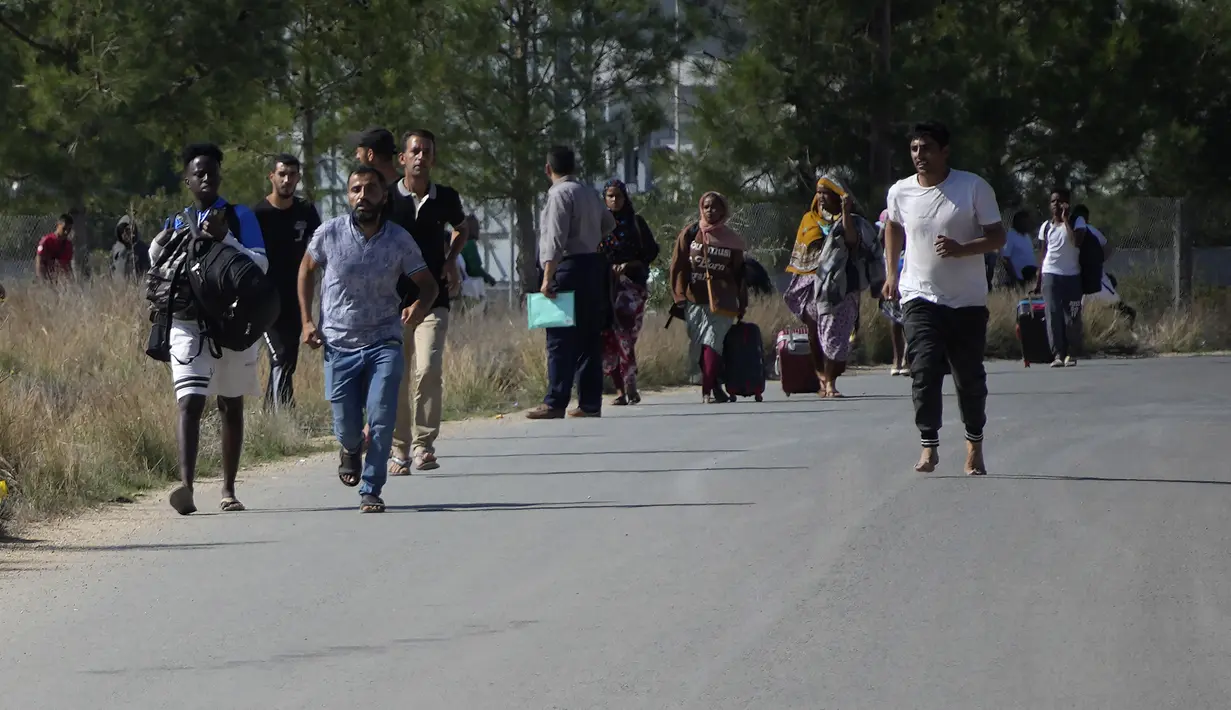 Para migran meninggalkan pusat penerimaan migran Pournara setelah pertempuran antara kelompok-kelompok yang bersaing di dalam kamp dekat desa Kokkinotrimithia, di pinggiran ibu kota Nicosia, Siprus, Jumat (28/10/2022). Kelompok-kelompok itu melemparkan batu dan mempersenjatai diri dengan tongkat dan batang logam. (AP Photo/Petros Karadjias)