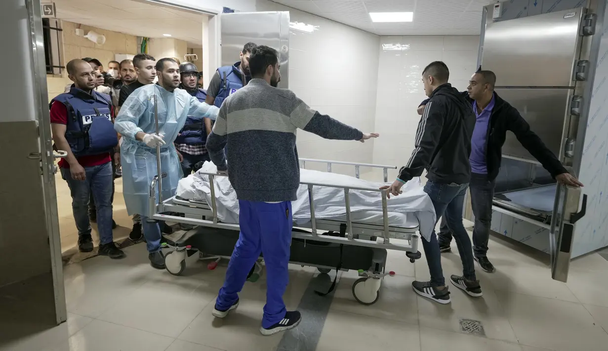 Wartawan dan petugas medis membawa jenazah wartawan Al Jazeera Shireen Abu Akleh ke kamar mayat rumah sakit di Kota Jenin, Tepi Barat, Rabu (11/5/2022). Menurut Kementerian Kesehatan Palestina, Shireen Abu Akleh tewas ditembak saat meliput serangan Israel di Kota Jenin. (AP Photo/Majdi Mohammed)