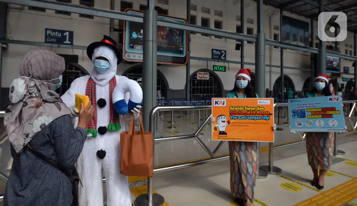 Petugas KAI yang mengenakan kostum Natal membagikan masker kepada calon penumpang di Stasiun Senen, Jakarta, Jumat (25/12/2020). Pembagian ini dilakukan untuk mengganti masker yang sudah dipakai calon penumpang selama perjalanan. (merdeka.com/Imam Buhori)