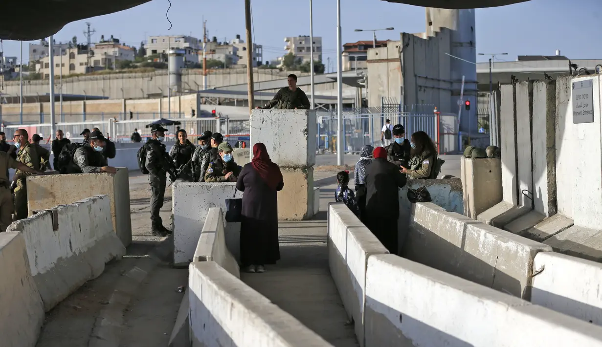 Anggota pasukan keamanan Israel berjaga-jaga di pos pemeriksaan Qalandia antara kota Ramallah Tepi Barat dan Yerusalem, ketika orang-orang Palestina menyeberang untuk menghadiri sholat Jumat kedua bulan Ramadhan di masjid Al-Aqsa, Jumat (23/4/2021). (ABBAS MOMANI / AFP)