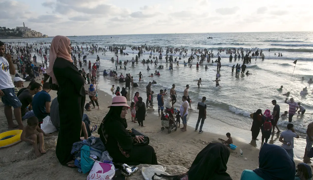 Warga Palestina melihat pengunjung yang tengah menikmati liburan di pantai Tel Aviv, Israel, Minggu (19/7/2015). Selama Idul Fitri, pemerintah Israel mengizinkan warga Palestina untuk berwisata di sepanjang garis pantai Mediterania. (REUTERS/Baz Ratner)