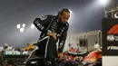 Pembalap Mercedes asal Inggris, Lewis Hamilton berlutut saat keluar dari mobilnya, sebagai dukungan kampanye gerakan Black Lives Matter, usai memenangi Grand Prix Formula Satu Bahrain di Sirkuit Internasional Bahrain, Sakhir, Minggu, (29/11/2020). (AFP/Hamad I Mohammed)