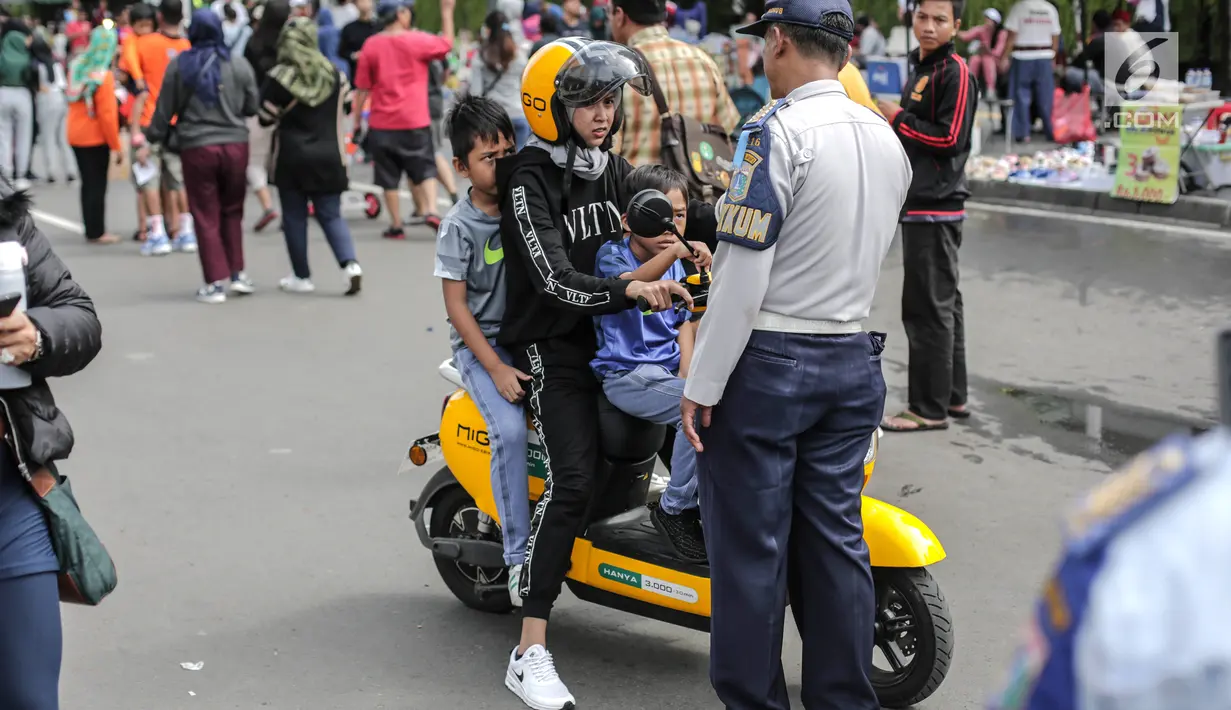 Petugas Dishub mensosialisasikan kepada pengendara sepeda motor listrik Migo saat melintasi CFD di Bundaran HI Jakarta, Minggu (17/2). Sosialisasi dilakukan karena tidak memenuhi teknis kendaraan bermotor di jalan raya. (Liputan6.com/Faizal Fanani)