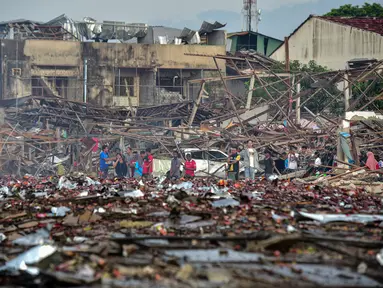 Orang-orang melihat rumah-rumah yang hancur akibat ledakan yang mengoyak gudang kembang api, di distrik Sungai Kolok di provinsi Narathiwat, Thailand selatan, pada 29 Juli 2023. (Madare TOHLALA / AFP)