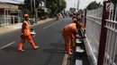 Petugas PPSU Kelurahan Kramat Jati mengecat ulang pagar pembatas Jalan Raya Bogor, Jakarta, Selasa (17/7). Pengecatan sebagai upaya perawatan berkala terhadap sarana dan prasarana yang sudah mulai kehilangan fungsi atau rusak. (Liputan6.com/Arya Manggala)