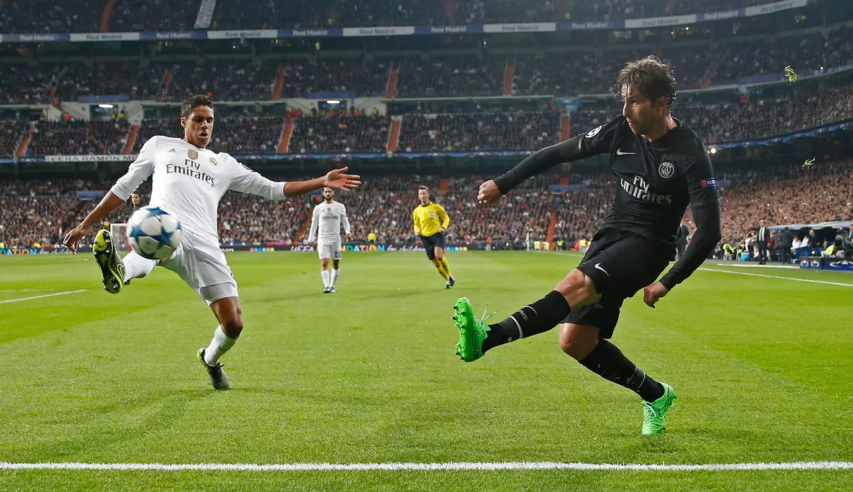 Bek PSG, Maxwell (kanan) mengumpan bola dari kejaran bek Real Madrid, Raphael Varane pada liga champions di stadion Santiago Bernabeu, Spanyol (3/11). Real Madrid menang atas PSG dengan skor 1-0. (Reuters/Juan Medina)
