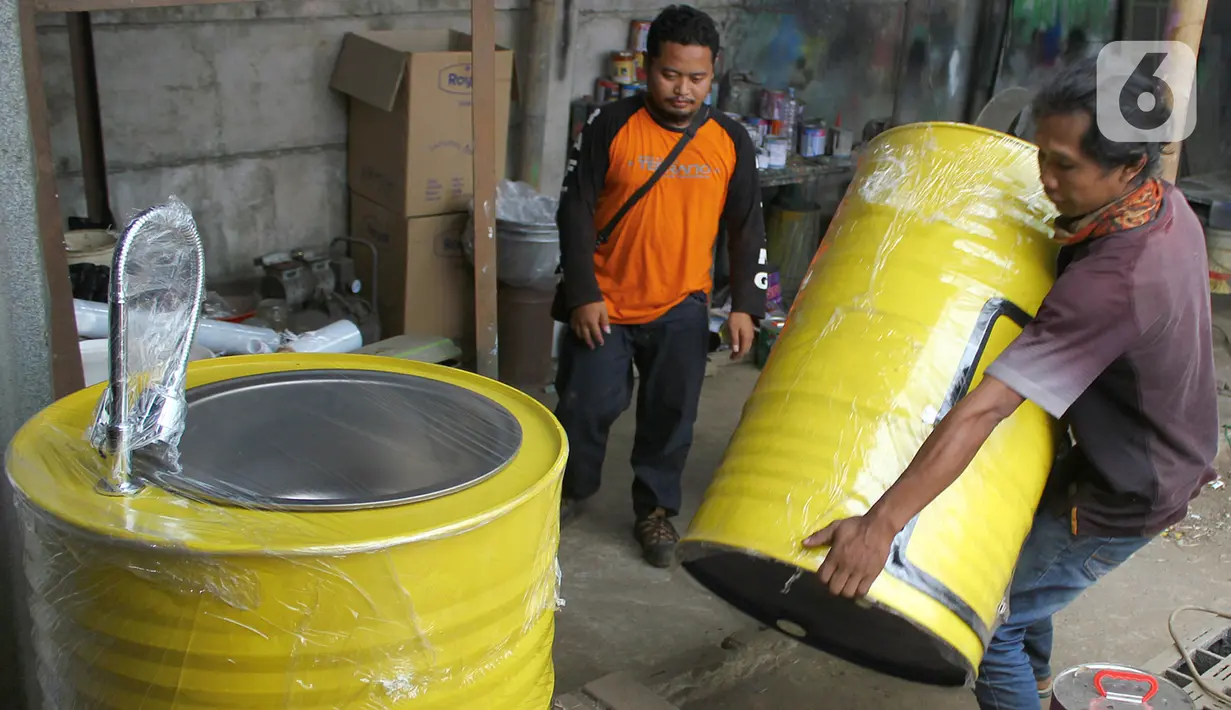 Perajin memproduksi wastafel portabel berbahan baku drum di workshop Galuh Creatives, Tangerang Selatan, Sabtu (30/5/2020). Wacana pemerintah menerapkan tatanan normal baru berimbas pada meningkatnya pesanan wastafel portabel yang dijual seharga Rp1,2 juta per unit. (merdeka.com/Arie Basuki)