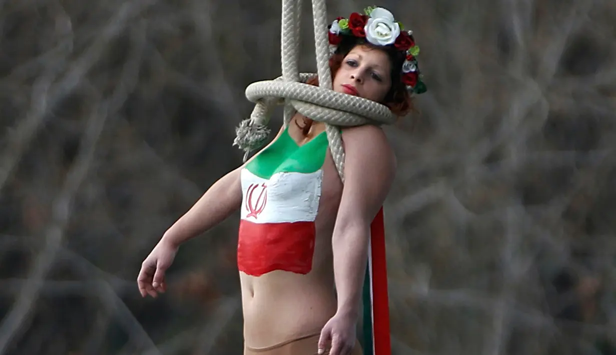 Aksi aktivis dari organisasi hak-hak perempuan Femen saat bergelantungan dari sebuah jembatan di Paris, Prancis, Kamis (28/1). Ia menggelar protes atas kunjungan Presiden Iran, Hassan Rouhani ke Paris. (REUTERS/Charles Platiau)