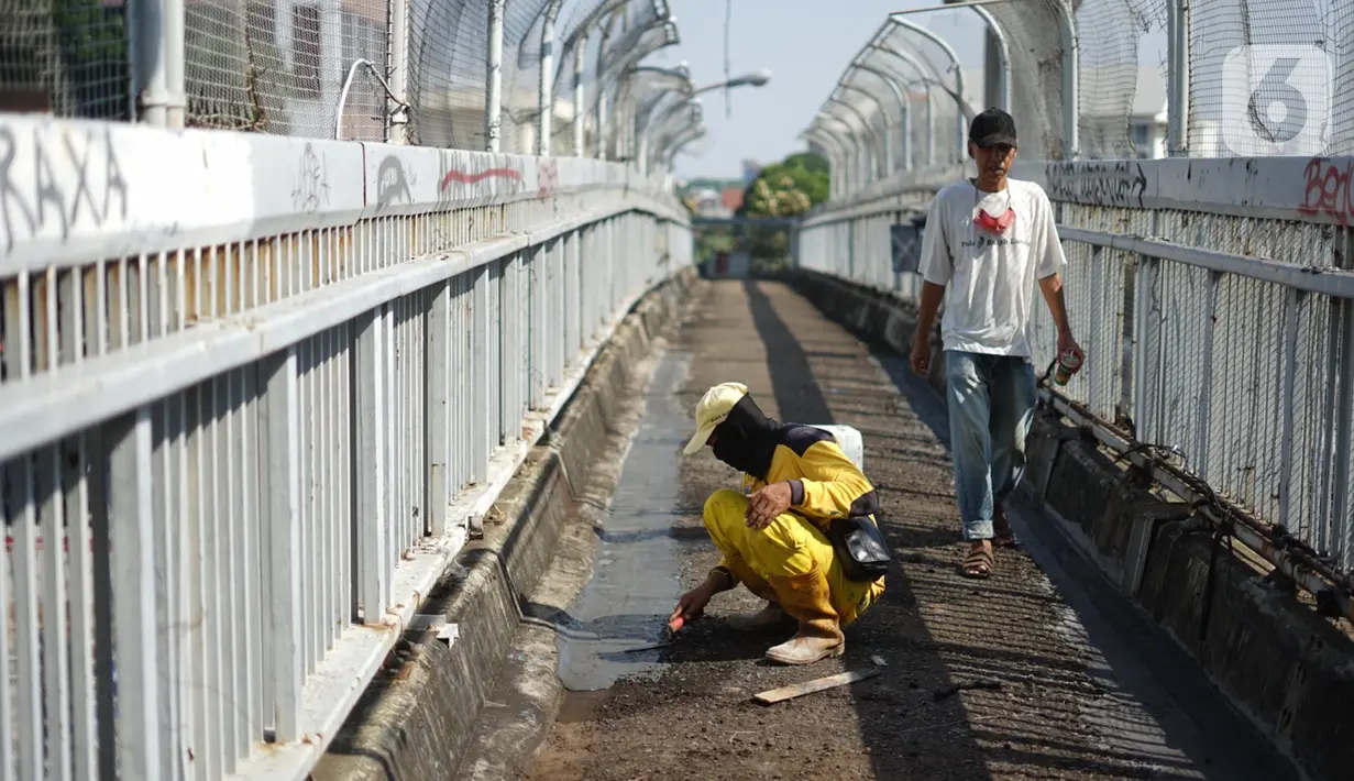 Petugas Bina Marga memerbaiki lantai Jembatan Penyeberangan Orang (JPO) yang berlubang di kawasan Tebet, Jakarta, Kamis (27/8/2020). Perbaikan dilakukan guna meningkatkan kenyamanan bagi pejalan kaki yang melintas. (Liputan6.com/Immanuel Antonius)