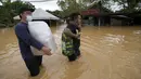 Warga membawa perbekalan kesehatan melalui jalan yang tergenang banjir di Hulu Langat, luar Kuala Lumpur, Malaysia, Minggu (19/12/2021). Banjir menyebabkan ribuan warga mengungsi dan banyak jalan yang memutus akses. (AP Photo/Vincent Thian)