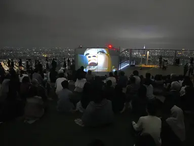 Pengunjung menonton film di rooftop dek observasi Shibuya Sky di Tokyo, Sabtu (9/10/2021). seminggu setelah Jepang sepenuhnya keluar dari keadaan darurat virus corona untuk pertama kalinya dalam lebih dari enam bulan. (AP Photo / Kiichiro Sato)