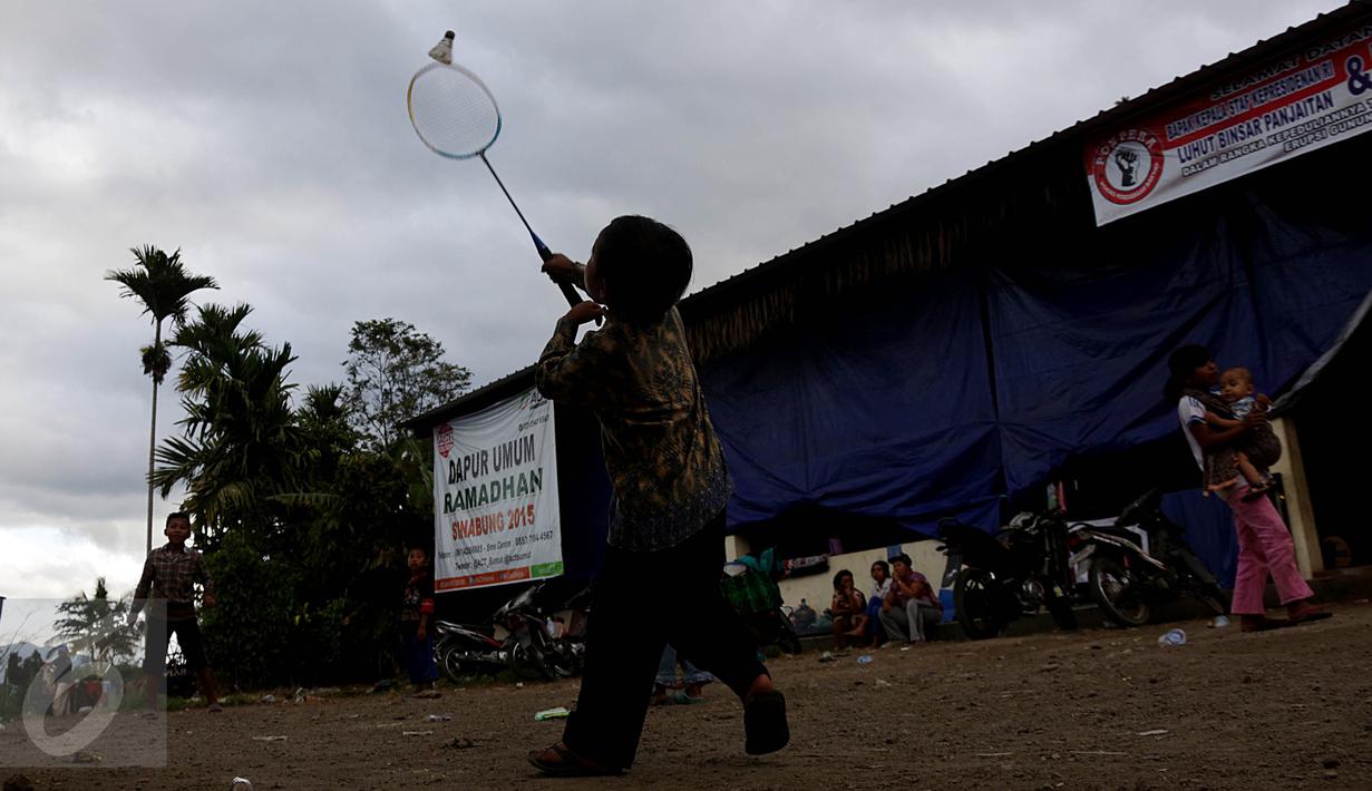 Seorang bocah tampak berusaha memukul kok saat bermain bulu tangkis di pengungsian Sinabung, Desa Batu Karang, Medan, Sabtu (4/7/2015). Sebanyak 1254 jiwa dari desa Gursinayan sudah mengungsi selama 1 bulan. (Liputan6.com/JohanTallo)