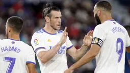 Los Blancos membuka kedudukan terlebih dahulu lewat gol cepat Gareth Bale (kiri) ketika babak pertama baru berjalan lima menit. Bale sukses menuntaskan umpan Benzema meski dirinya dikawal oleh dua pemain. Papan skor berubah menjadi 1-0 atas keunggulan Real Madrid. (Foto: AP/Alberto Saiz)