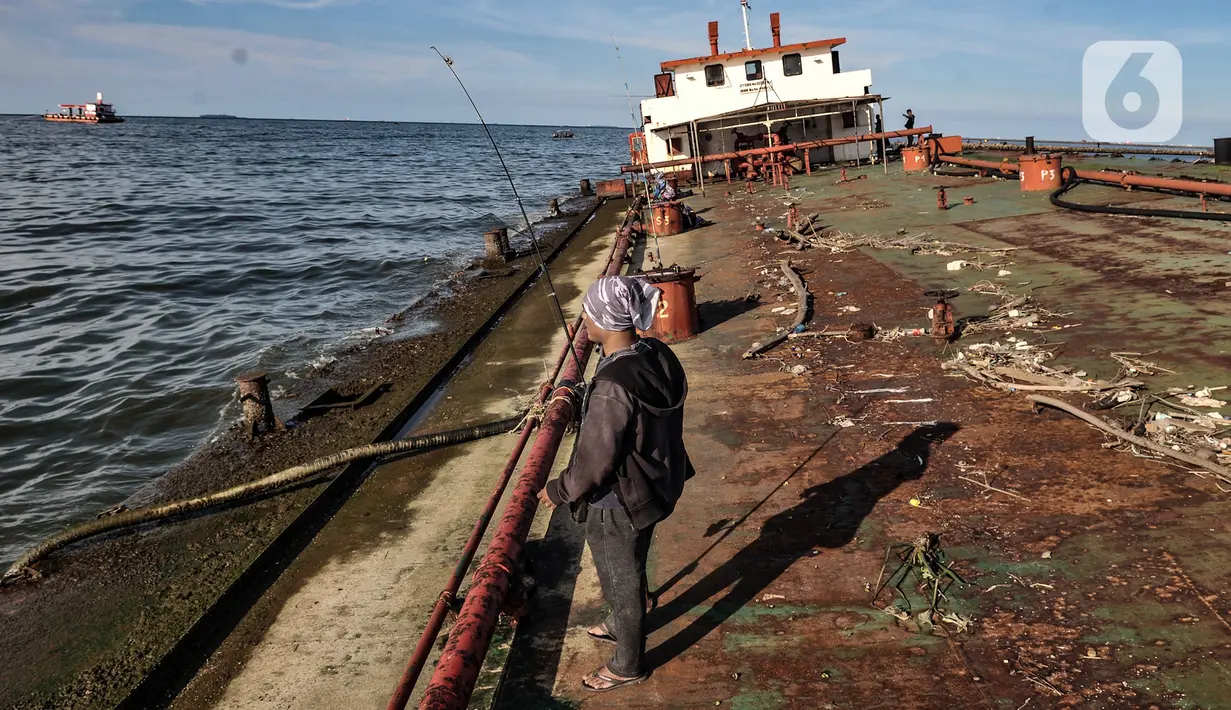 Aktivitas warga memancing di atas sebuah kapal karam di pesisir Kali Adem, Muara Angke, Jakarta, Minggu (27/12/2020). Sebuah kapal yang telah karam selama bertahun-tahun tersebut dimanfaatkan oleh warga sebagai tempat memancing meskipun berisiko membahayakan keselamatan. (merdeka.com/Iqbal Nugroho)